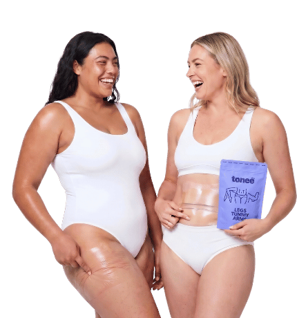 Two women laughing together, one holding a Tonee Legs, Tummy & Arms pack